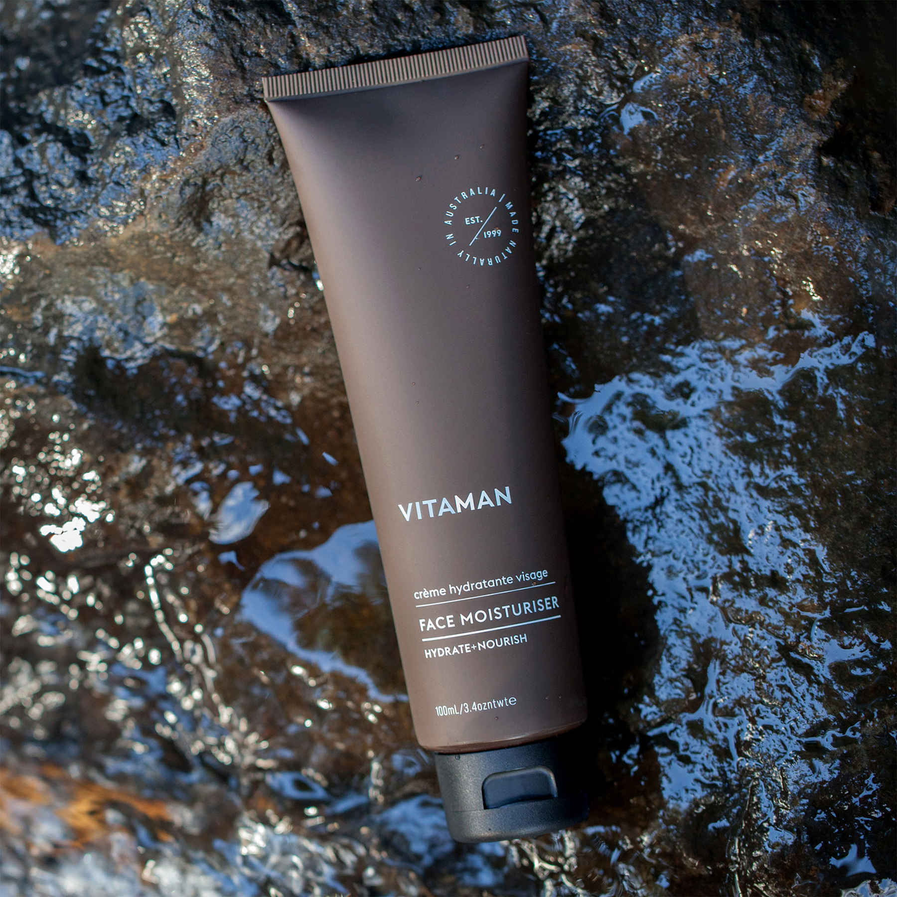VITAMAN face moisturiser for men placed on wet natural stone background