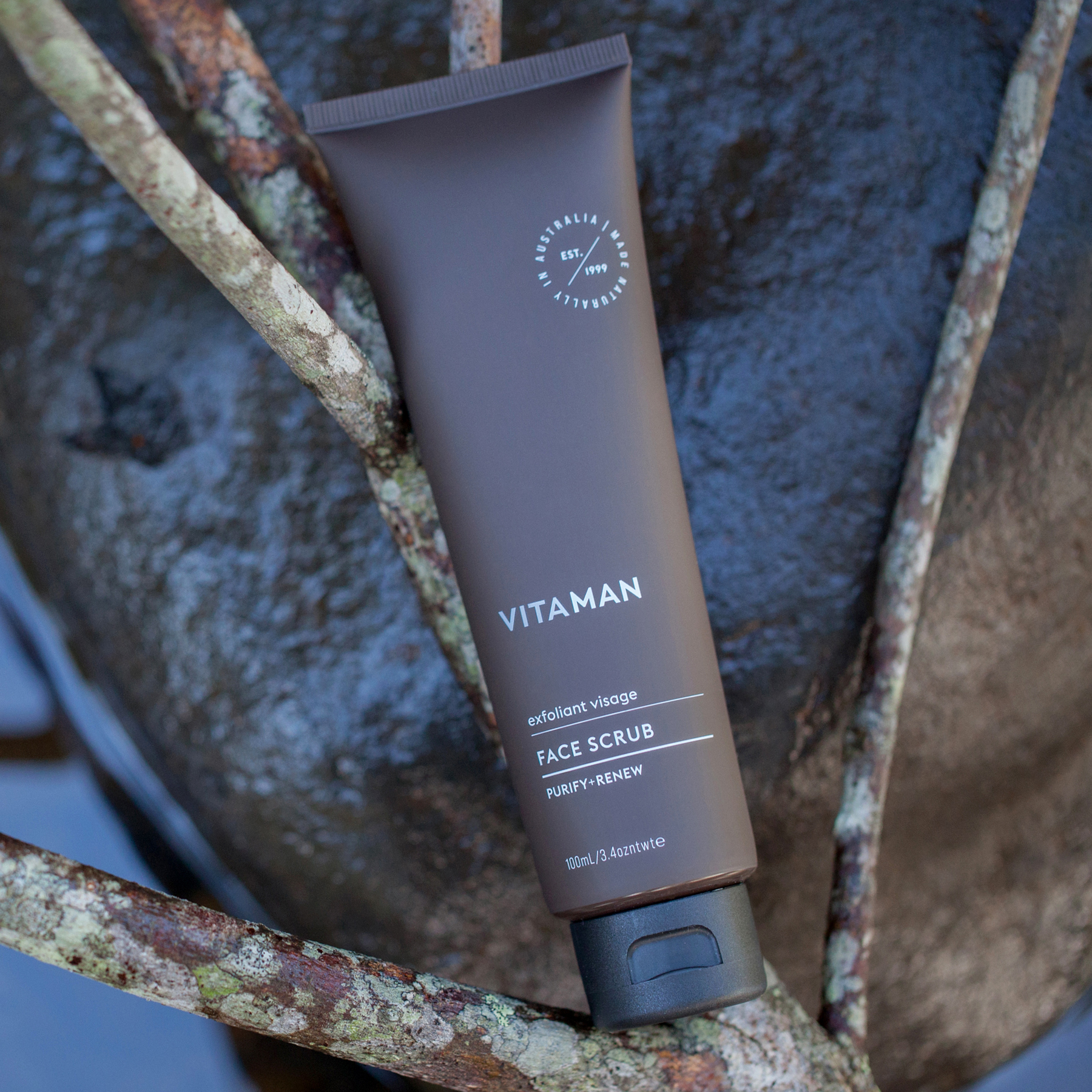 VITAMAN face scrub exfoliating cleanser for men displayed in natural outdoor setting