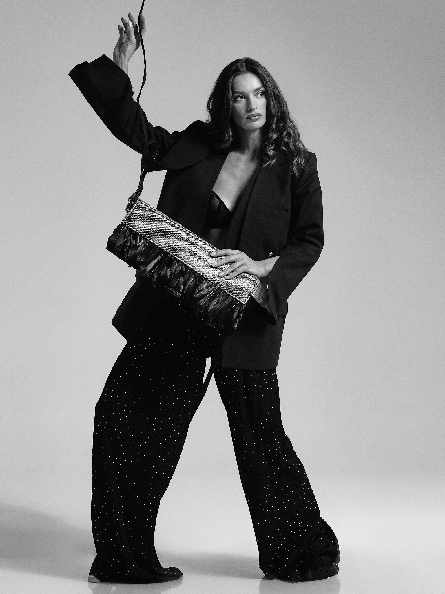 Model wearing a black tailored look and holding a handcrafted GUROSI bag, showcasing the brand’s artisanal design and contemporary elegance.