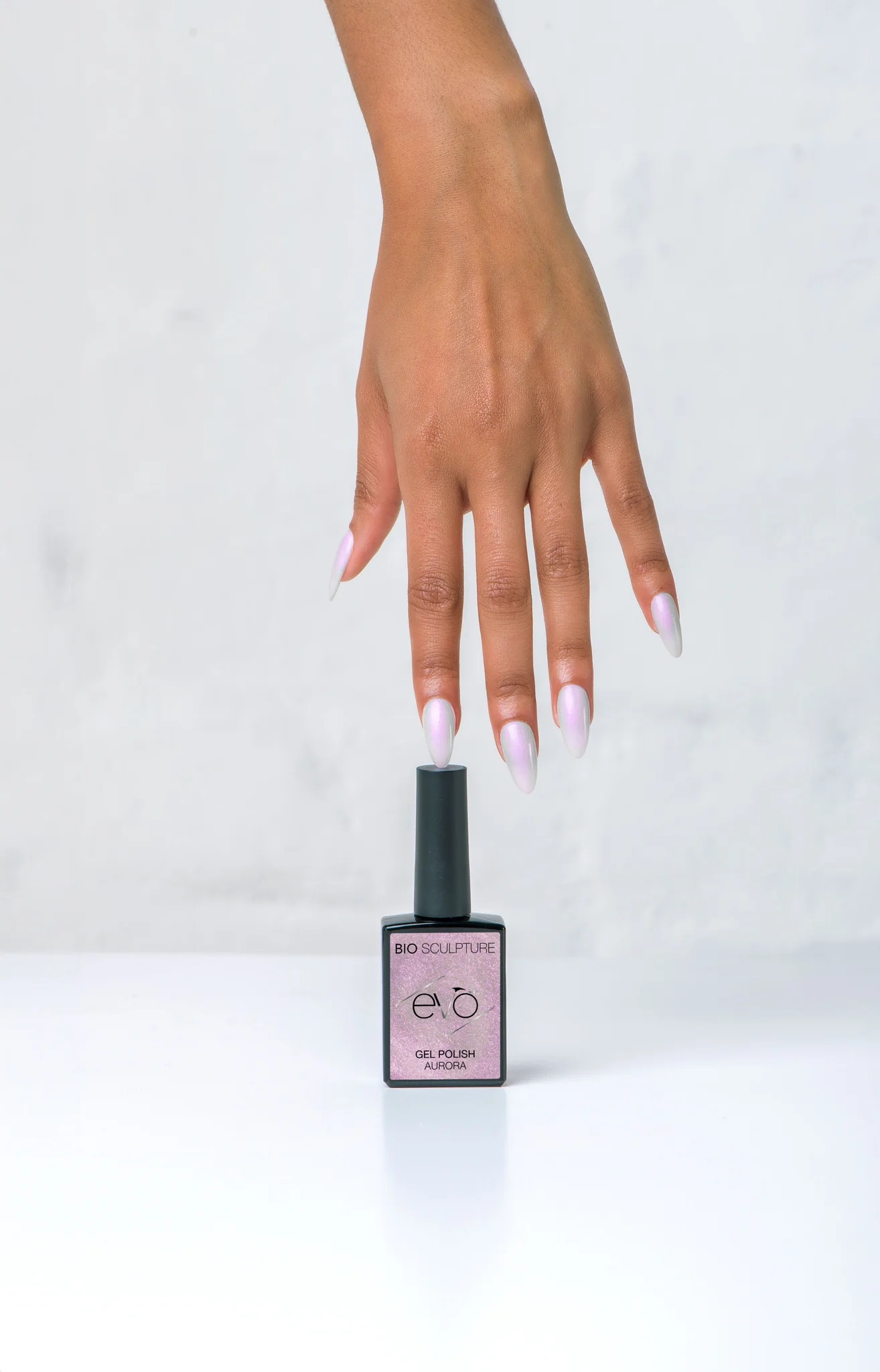 Model wearing soft pink shimmer gel polish “Aurora” by Bio Sculpture EVO on almond-shaped nails