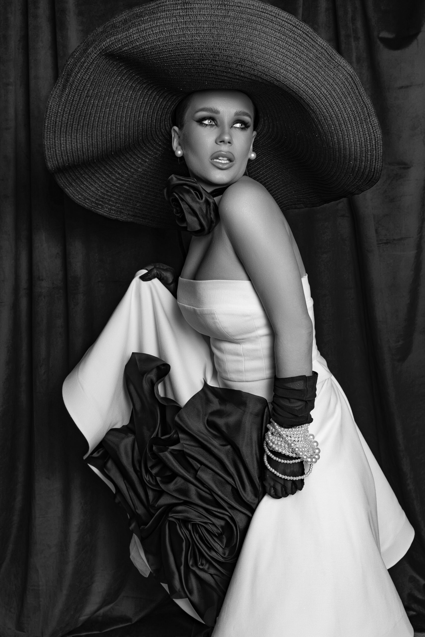 Black and white portrait of a model wearing a structured couture dress and wide-brim hat by TutTrostyle.