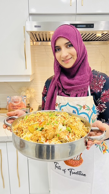 Rumina Rizvi in her kitchen, proudly presenting a fresh pot of biryani — the dish she calls a family favourite and a taste of home.